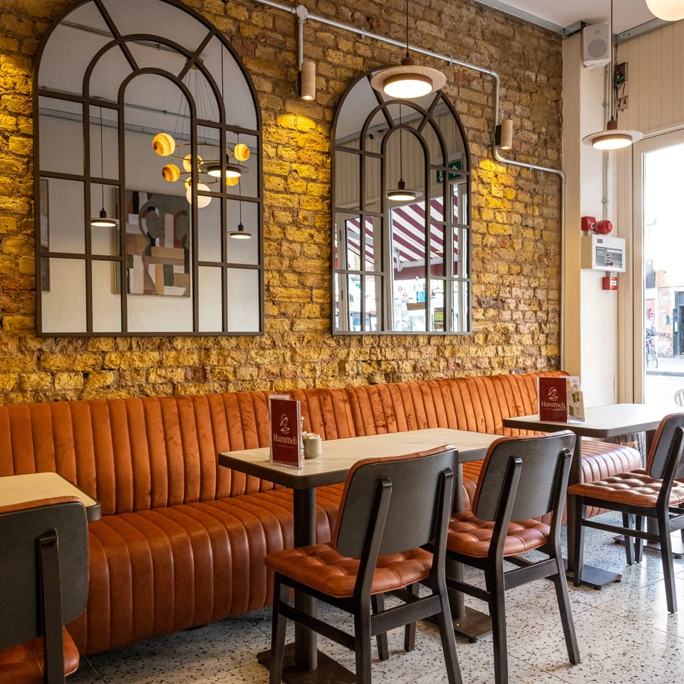 Leather banquette under arched mirrors on the exposed brick wall, looking out to Stoke Newington Road