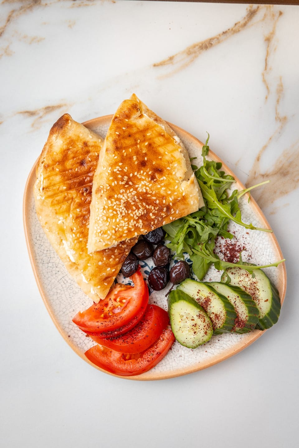 Toasted sesame bread with cheese, rocket, tomato and olives